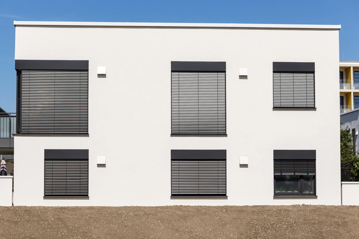 Façade moderne d'immeuble résidentiel avec volets roulants métalliques noirs sur baies vitrées