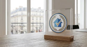Gros plan professionnel du logo ou du certificat de certification Qualibat, présenté de manière claire sur une surface professionnelle neutre avec un éclairage naturel mettant en avant les éléments visuels distinctifs de la certification. Alternative : présentation visuelle d'un logo ou badge officiel reconnu dans le secteur du bâtiment et de la construction, photographié dans un style professionnel et minimaliste.