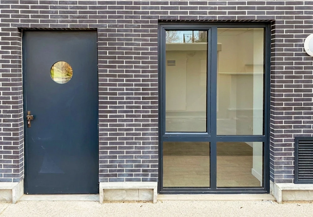 Façade extérieure d'habitation avec volets battants fermés en aluminium blanc à lames orientables