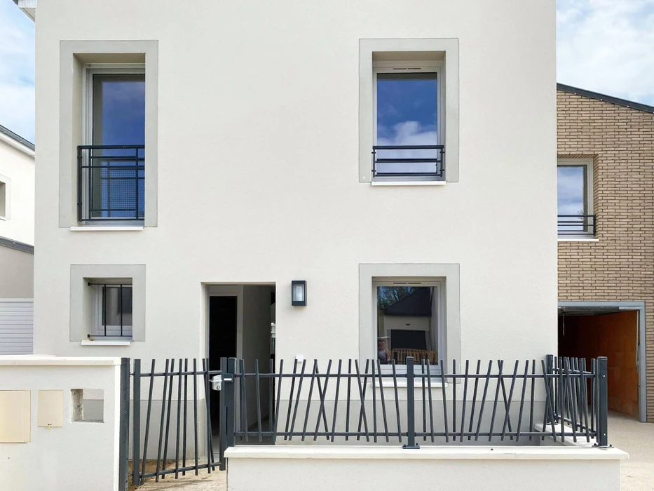 Façade extérieure d'habitation avec volets battants fermés en aluminium blanc à lames orientables