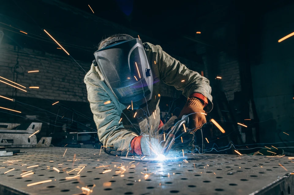 Mains d'artisan travaillant sur serrure à cylindre, outils de serrurier étalés sur établi en bois